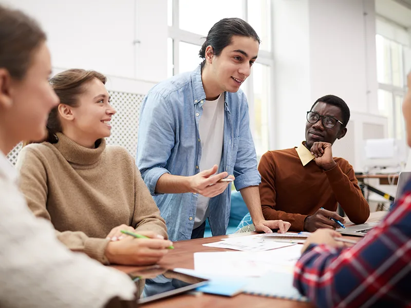 Large group of students working together on team project while studying in college