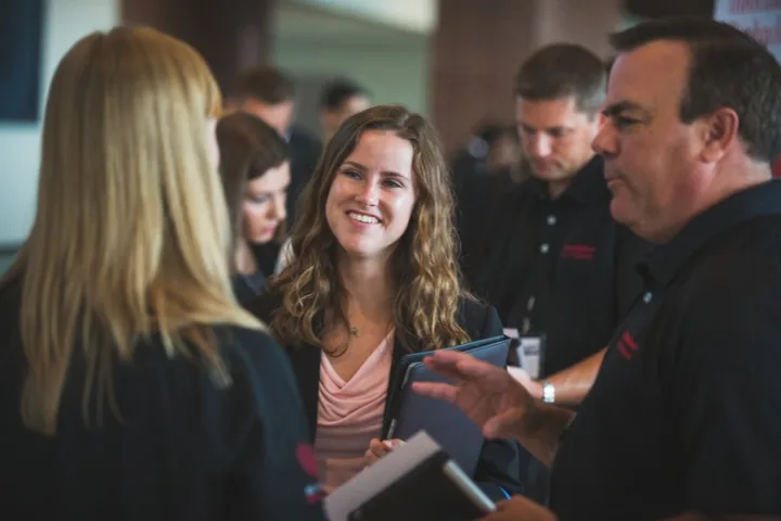 Student in professional attire is surrounded by others at career fair