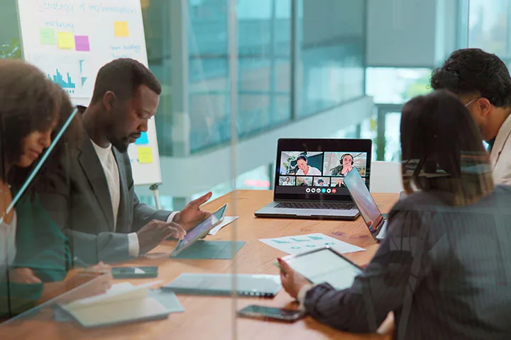 People sitting around conference room table looking at computer.