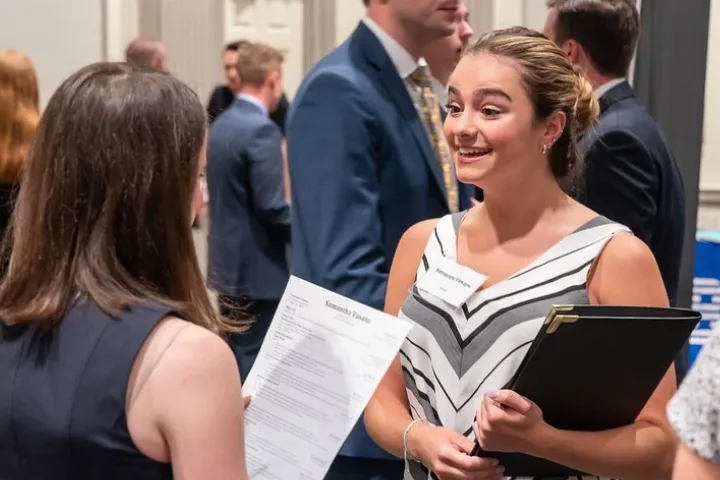 Student in business casual holding a portfolio at a career fair