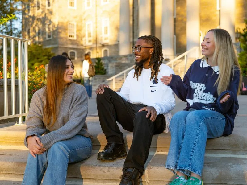 Three students talk on outdoor stairs