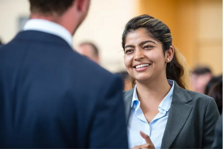 Student in a suit speaks to another networking event attendee