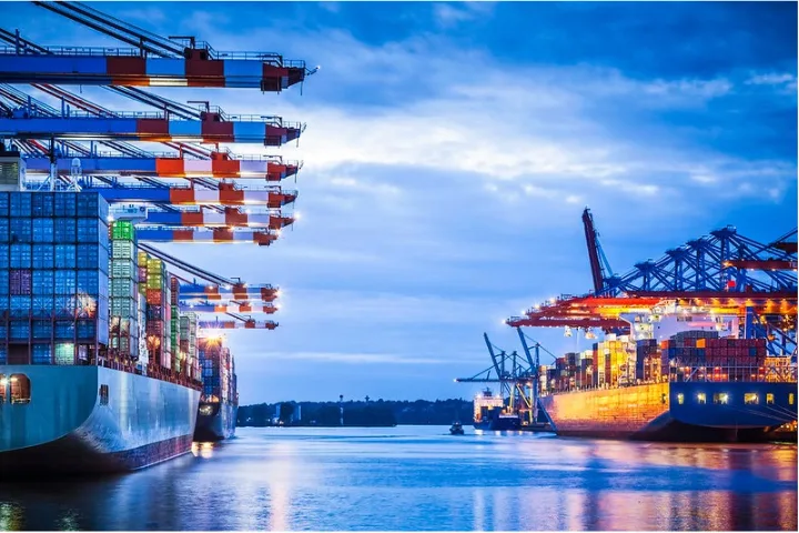 Several boats with shipping containers on the water