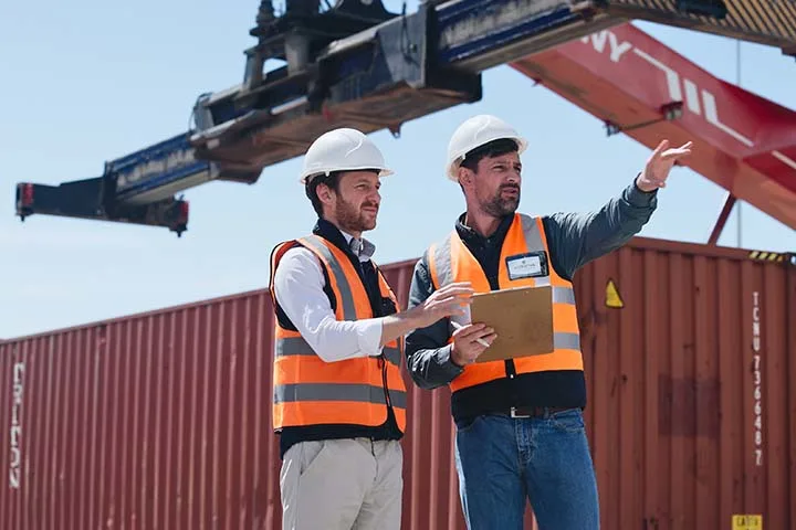 Two workers navigating containers