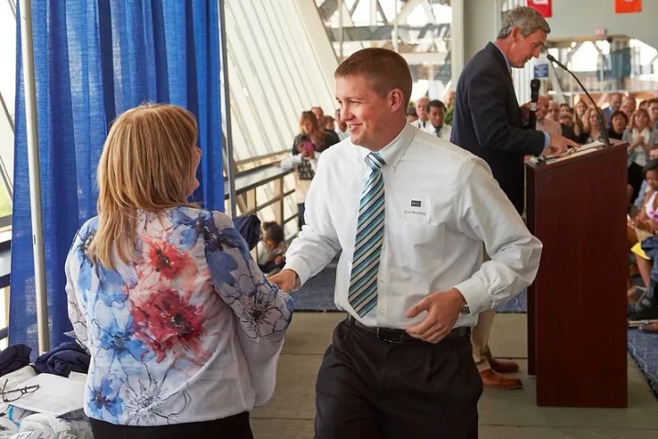 Graduating student shakes hands with a woman during commencement