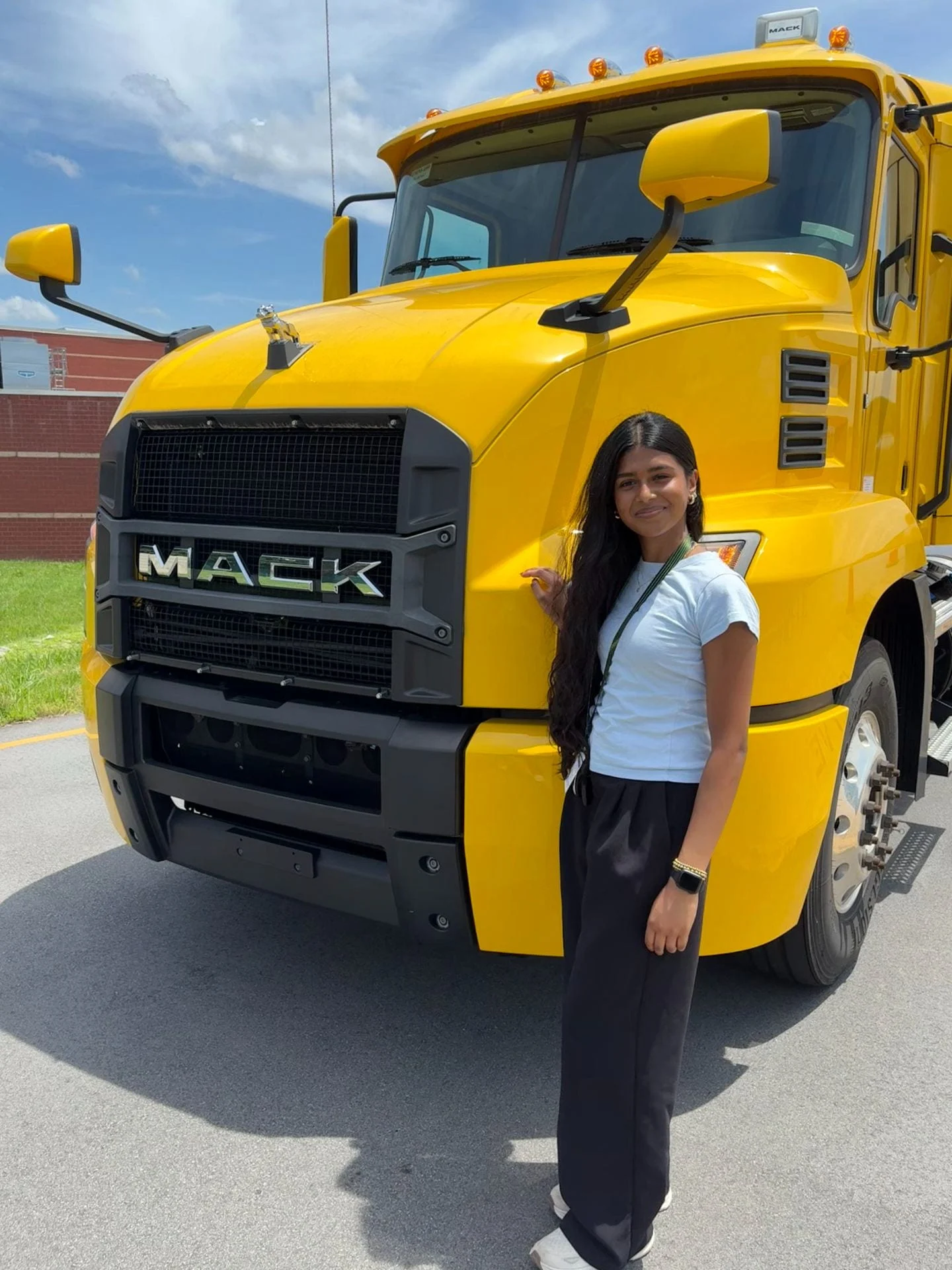 Varsitaa Gunaseelan standing by yellow Mack truck.