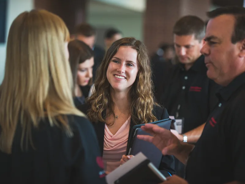 Student in professional attire smiles at a crowd