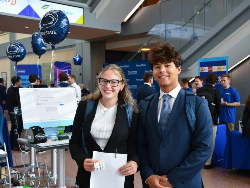 Two students in professional attire smile