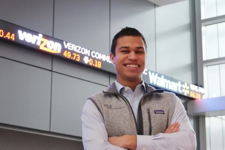 Kevin Hernandez, a previous Lion Fund leader, stands in front of a stock ticker