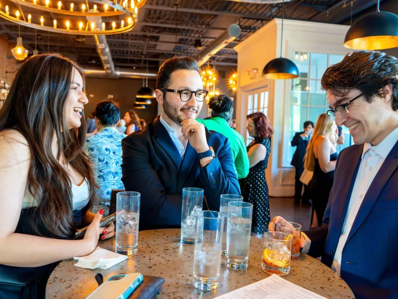 Three people stand at a table at the Grad Gala