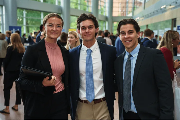 Three Smeal students in professional business attire attend a career fair in the Business Building atrium. 