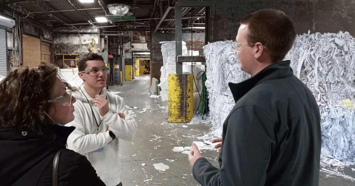 Photo of Ben Krantwiess talking with others inside a paper plant