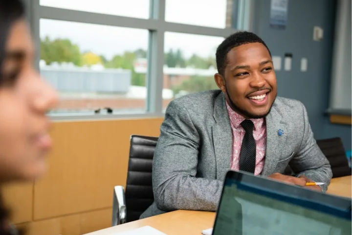 Man in a suit sits at a table with others
