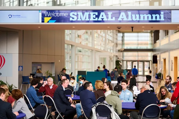 Crowd sits at tables at a Smeal Alumni event