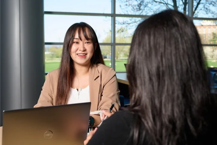 Two students talk over laptops