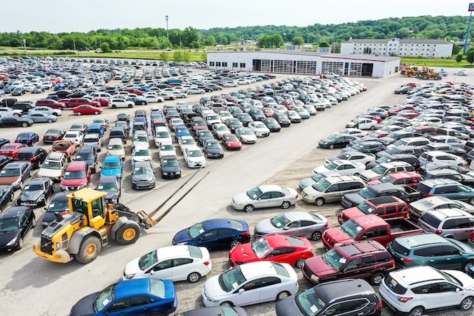 Lot of cars with forklift driving through