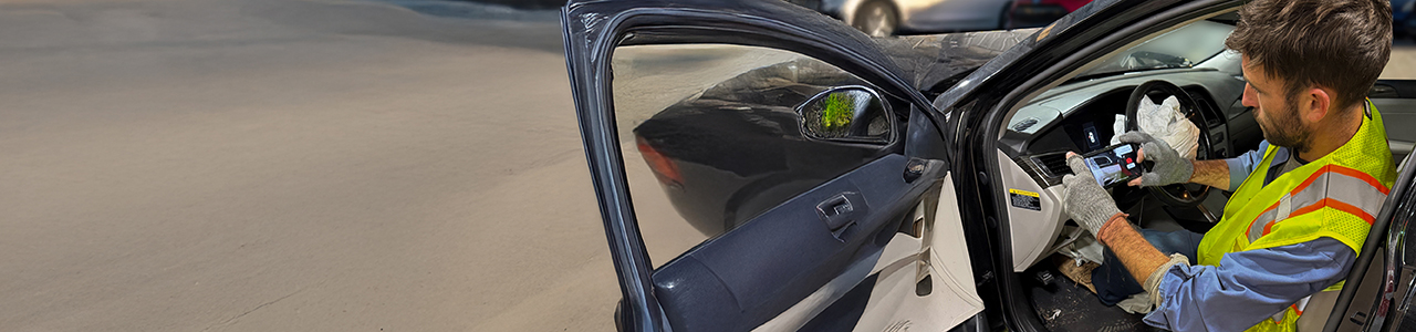 Man sitting in a car with a mobile phone taking a picture of the mileage.