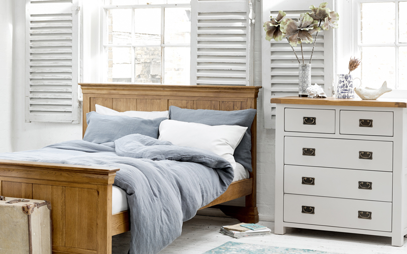 aegean style bedroom with oak bed and white painted chest of drawers