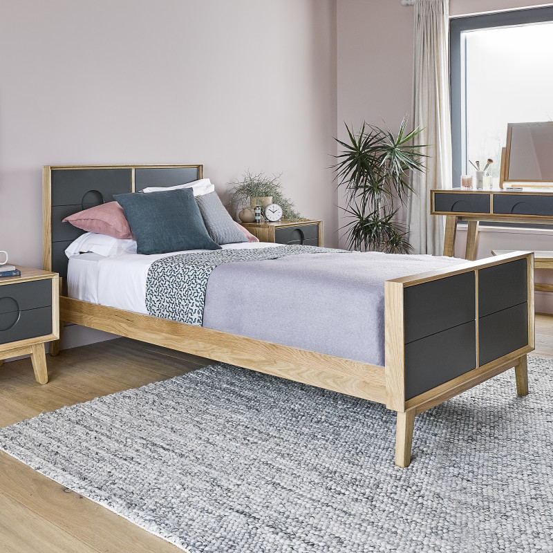 Grey painted and natural oak single bed with dressing table and bedside table in a pink bedroom. 