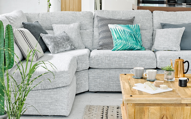 Large light grey corner sofa with botanical cushions