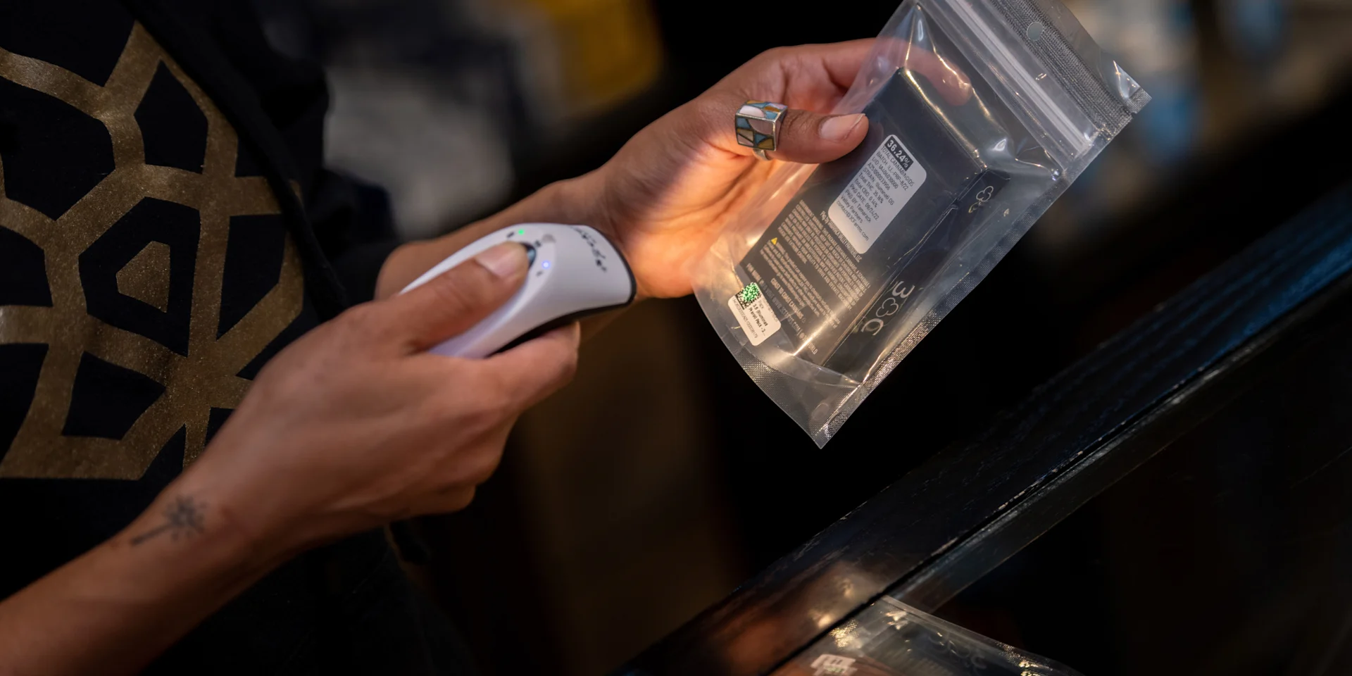 A staff member scans the compliance tag on a sealed cannabis package before it leaves the premises.