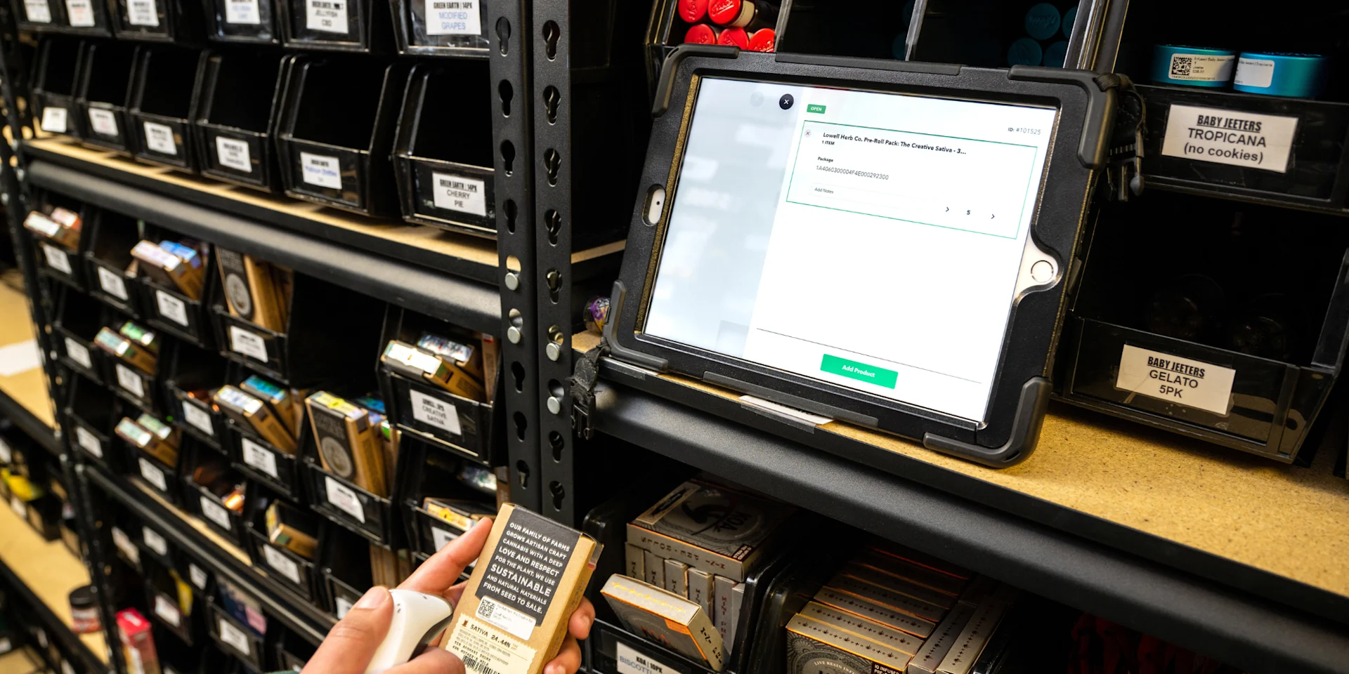 A dispensary employee scans a product into inventory while the package details appear on a tablet.