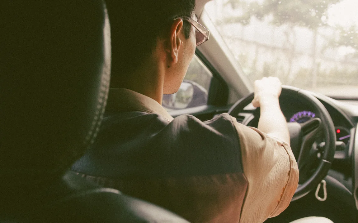 A cannabis delivery driver behind the wheel on a delivery route.