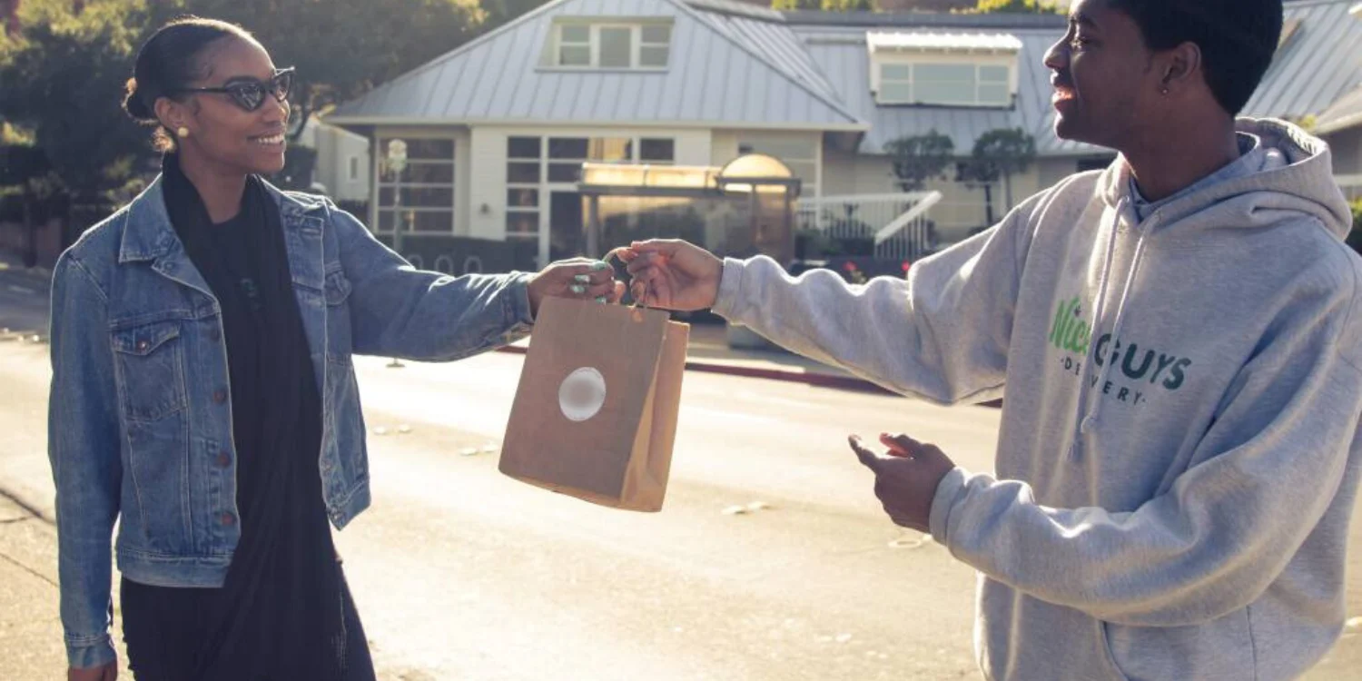 Cannabis delivery driver handing off an order to a customer