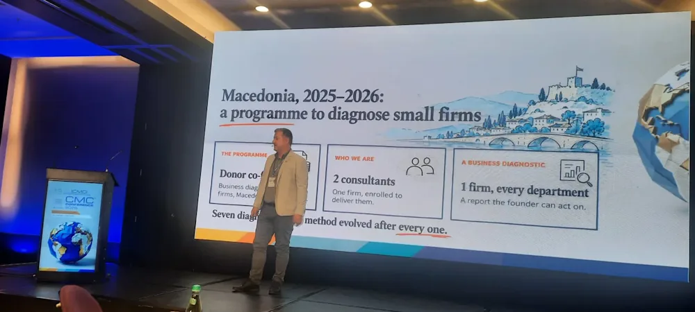 Dancho Dimkov on stage at the 13th International CMC Conference in Bucharest, beside a slide that reads Macedonia, 2025-2026: a programme to diagnose small firms.