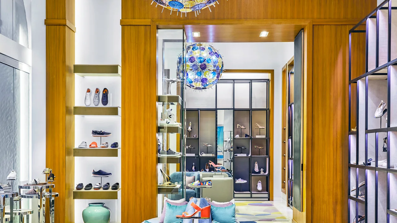 Modern shoe store interior with blue velvet chairs, wooden shelving displaying colorful footwear.
