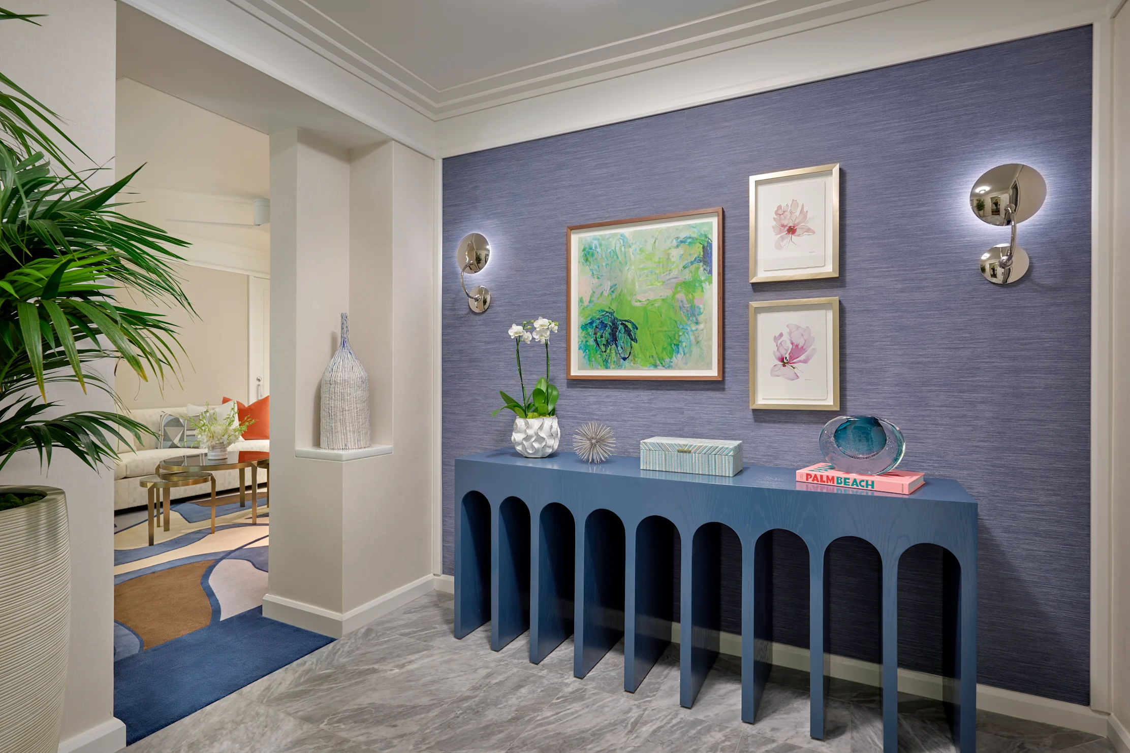 Modern entryway with blue console table, textured navy wall, framed artwork, and decorative accents.