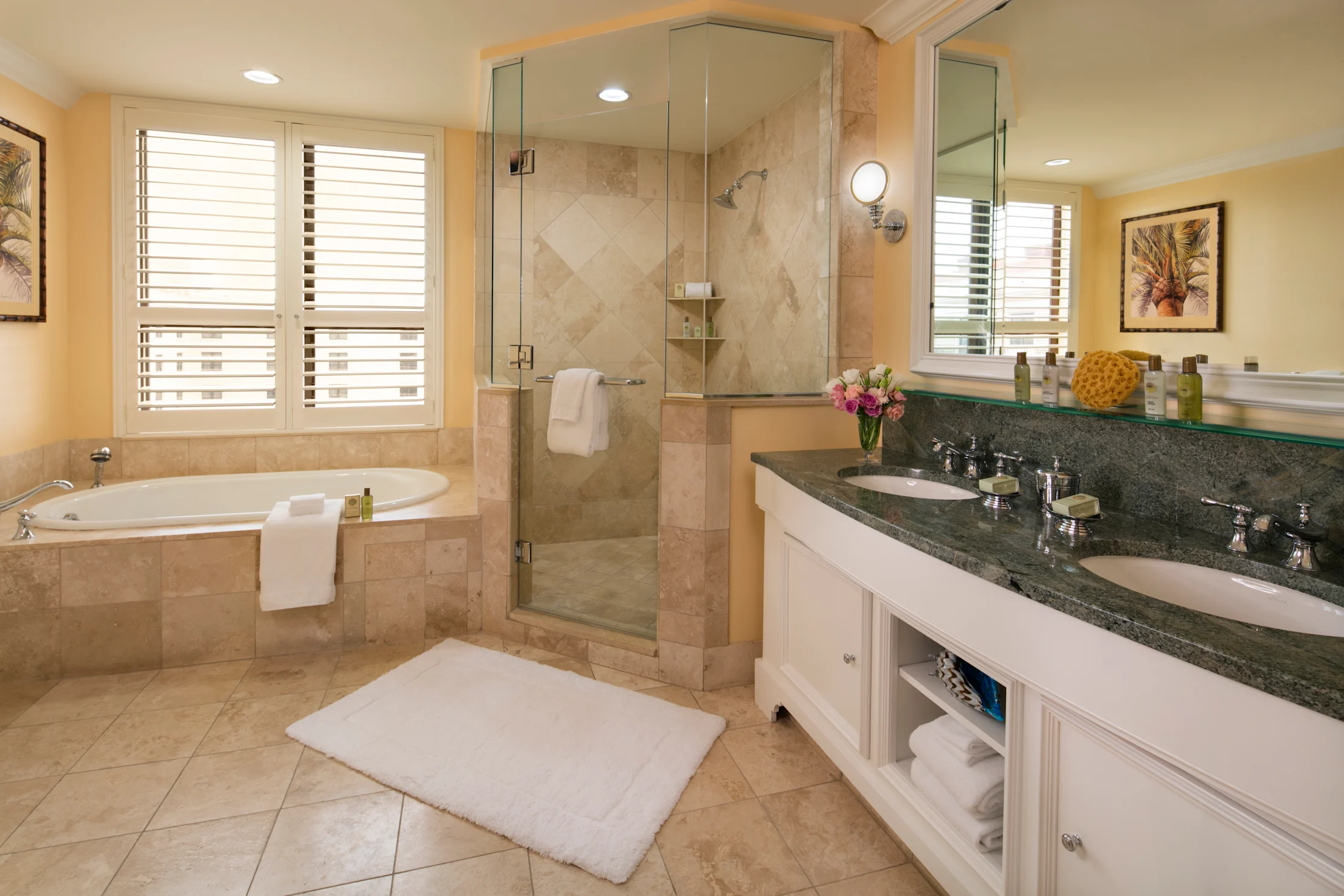 Luxury bathroom with beige tile, glass shower, soaking tub, double vanity with granite countertop.
