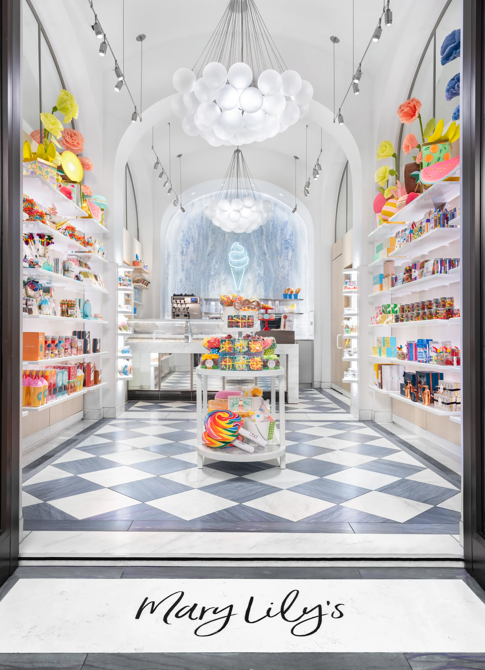 Bright white candy store interior with colorful paper flowers, bubble chandeliers, and checkered floor.