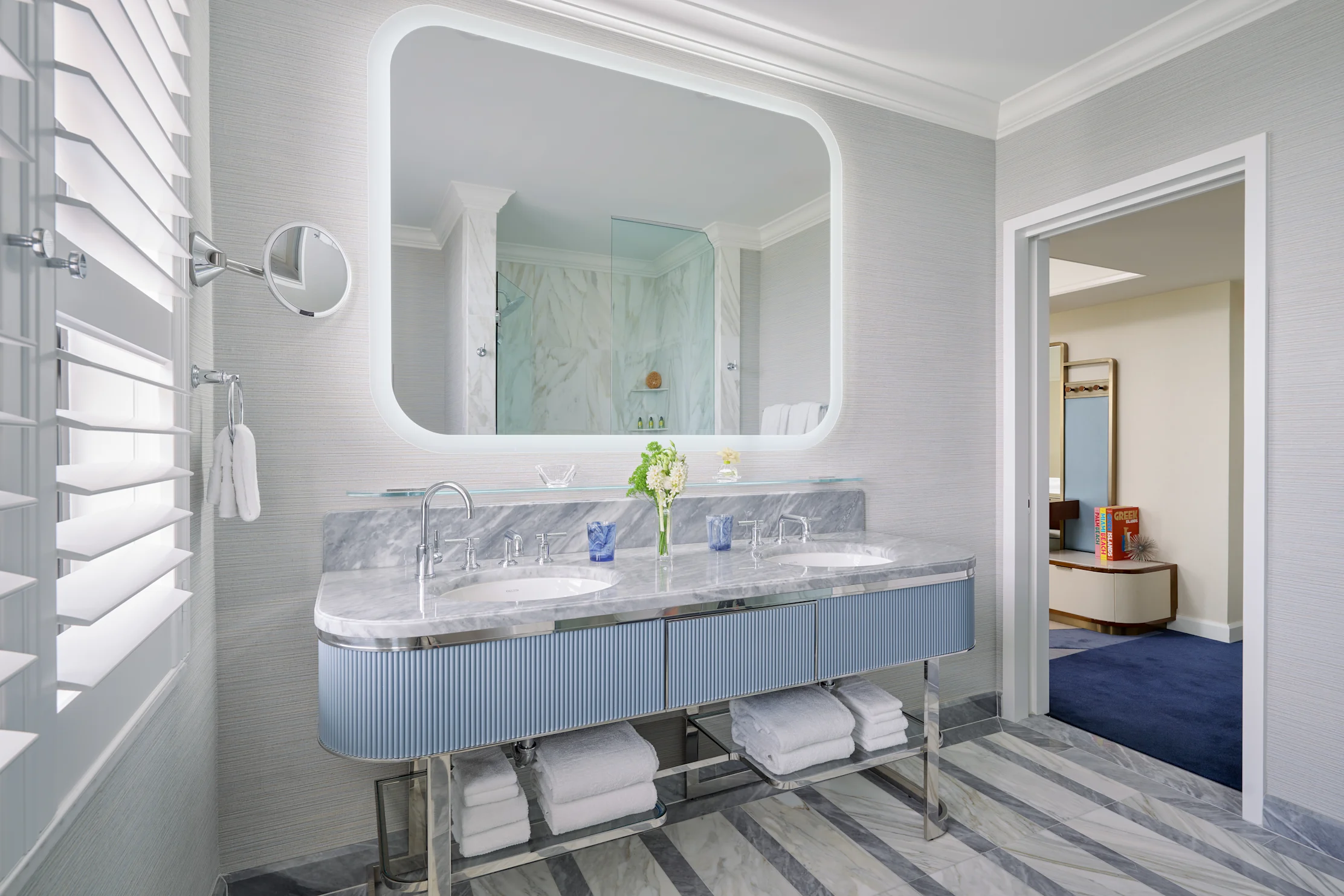 Modern luxury bathroom with double marble vanity, backlit mirror, glass shower, and gray walls.