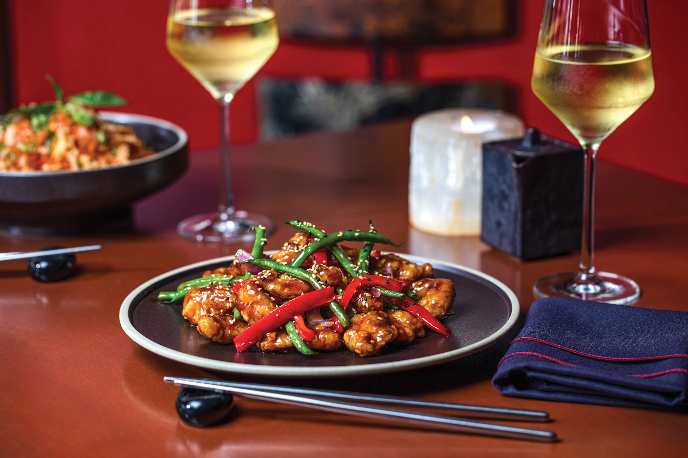 Asian stir-fry dish with sesame seeds, green beans, and red peppers served with white wine.