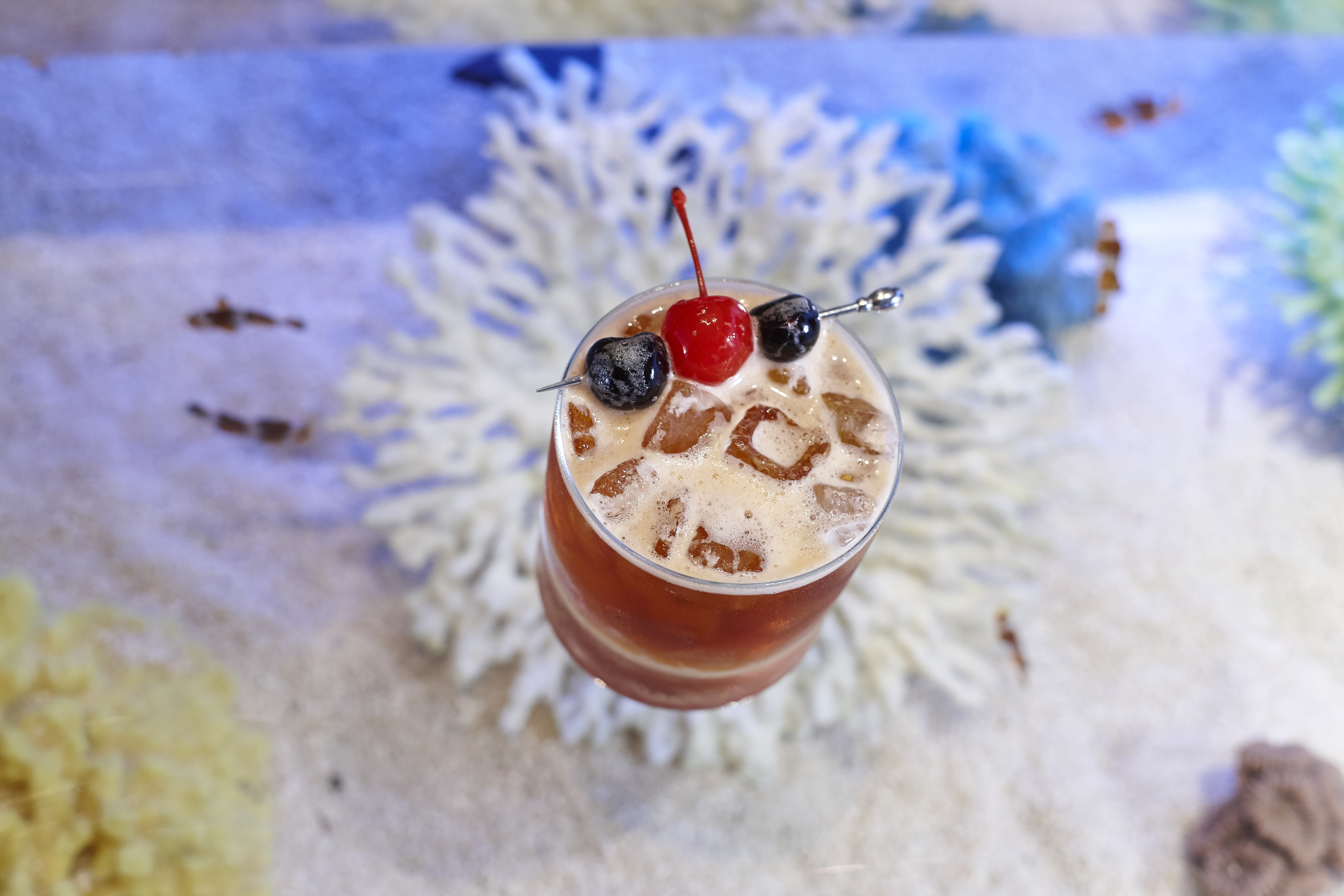 Cocktail with ice and cherries on a colorful map background