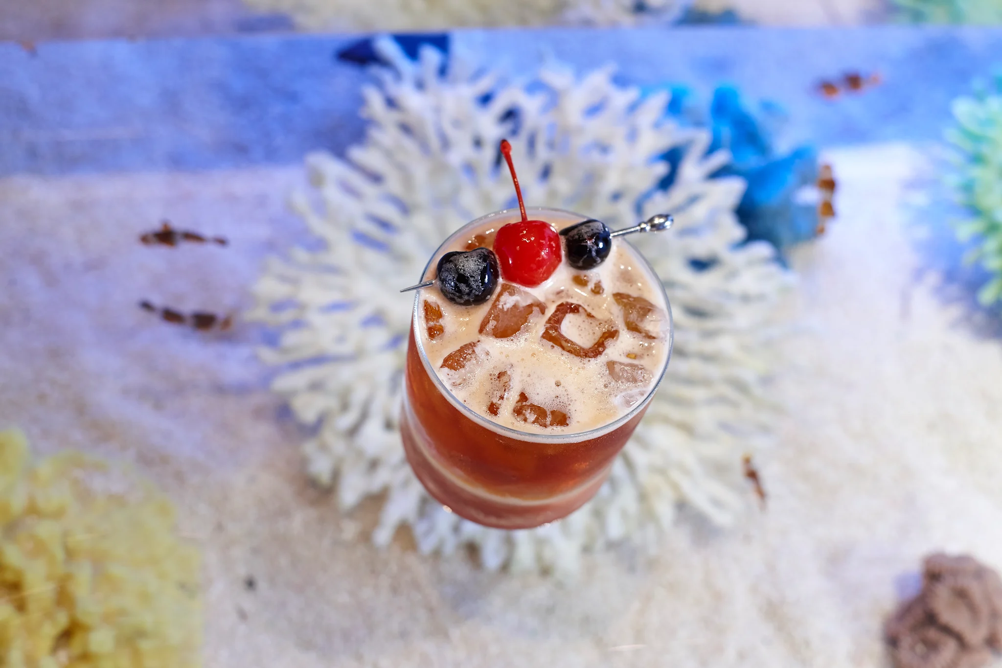 Cocktail with ice and cherries on a colorful map background
