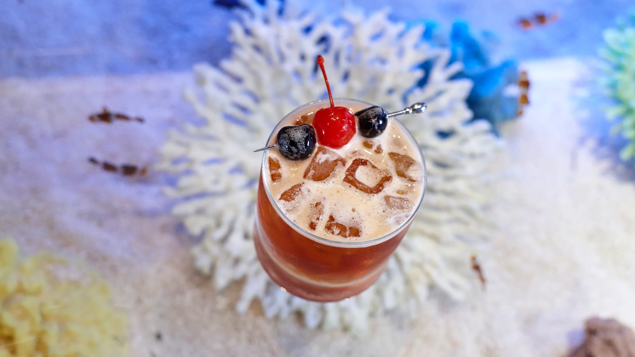 Cocktail with ice and cherries on a colorful map background