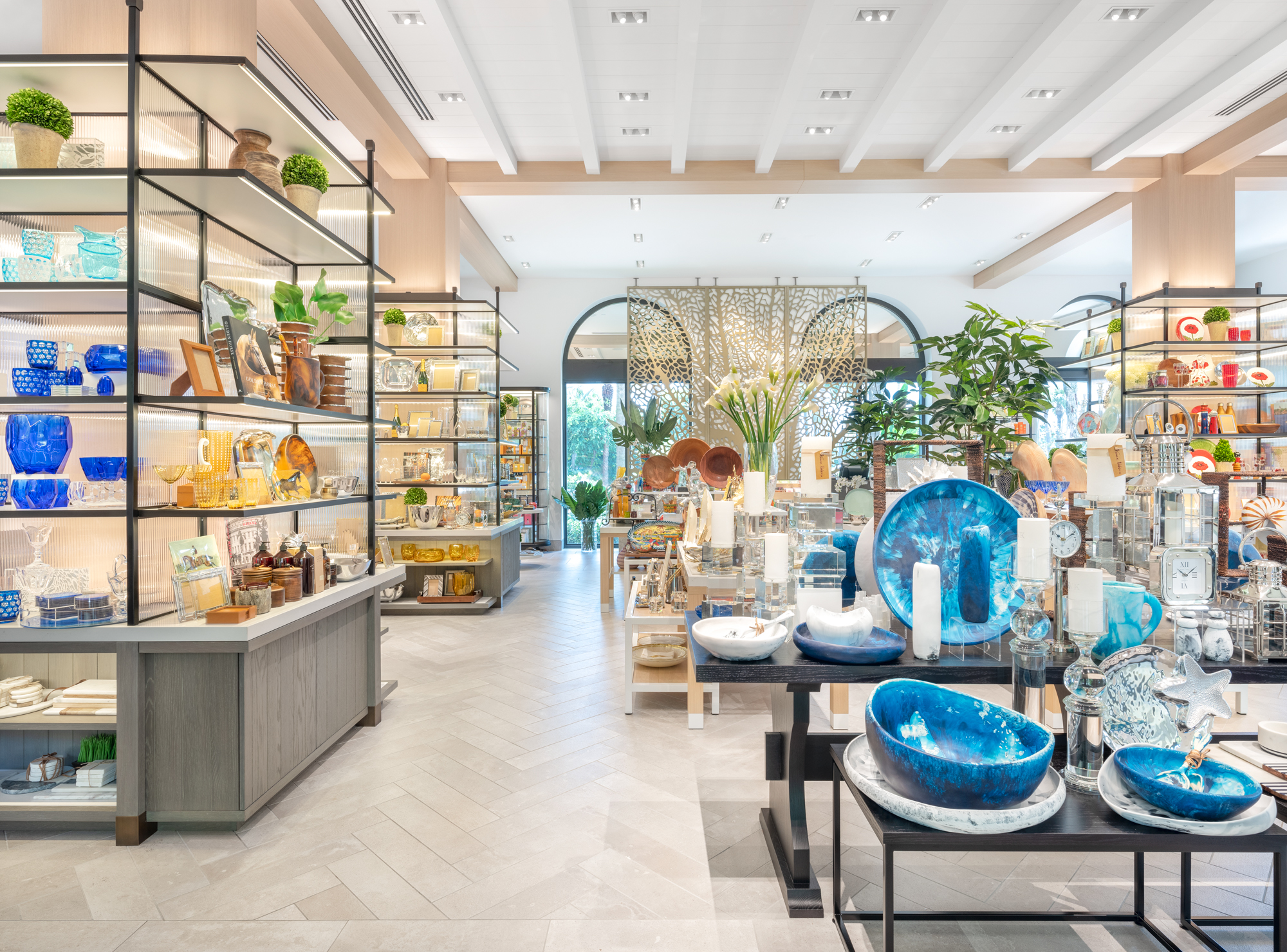 Bright modern home decor store with blue ceramics, plants, and colorful items on shelves and tables.