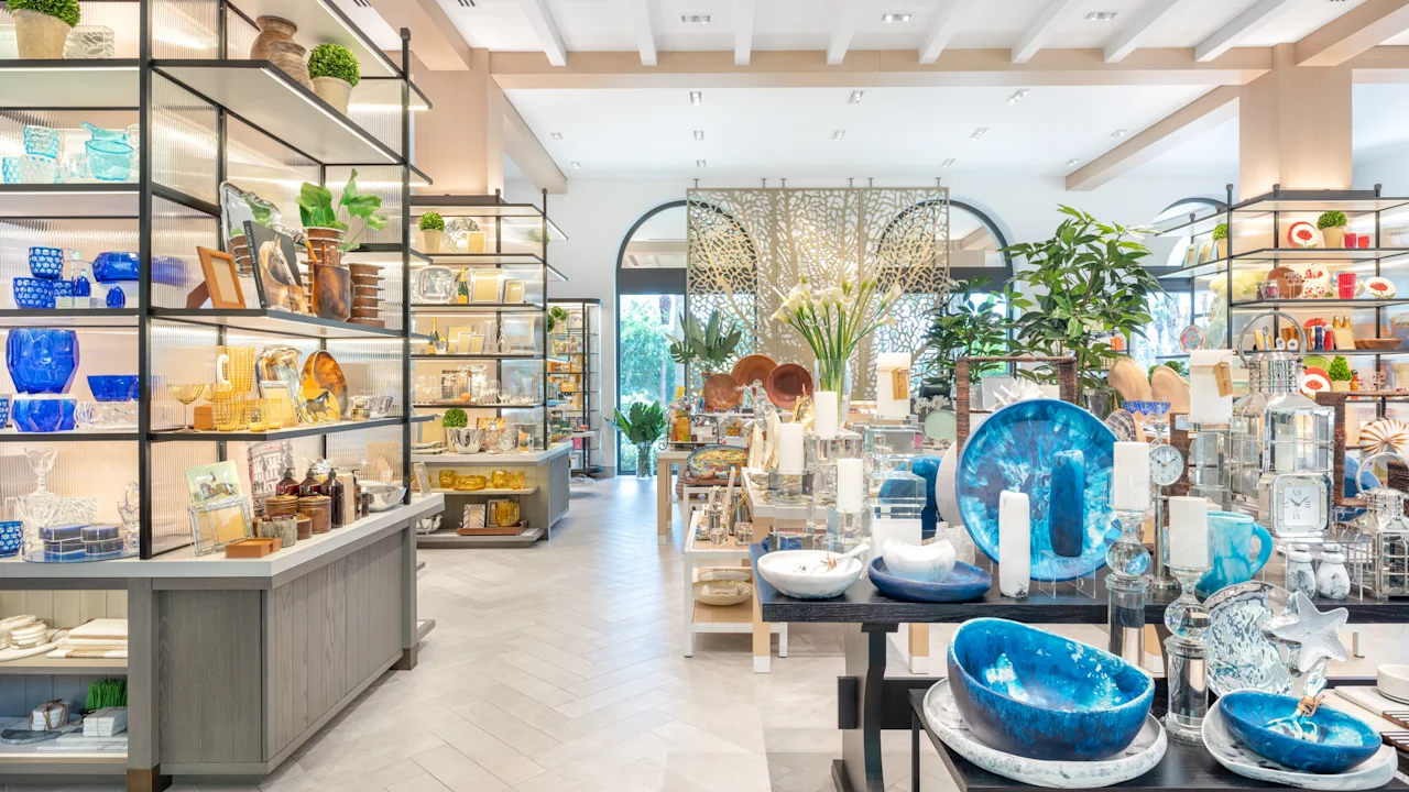 Bright modern home decor store with blue ceramics, plants, and colorful items on shelves and tables.