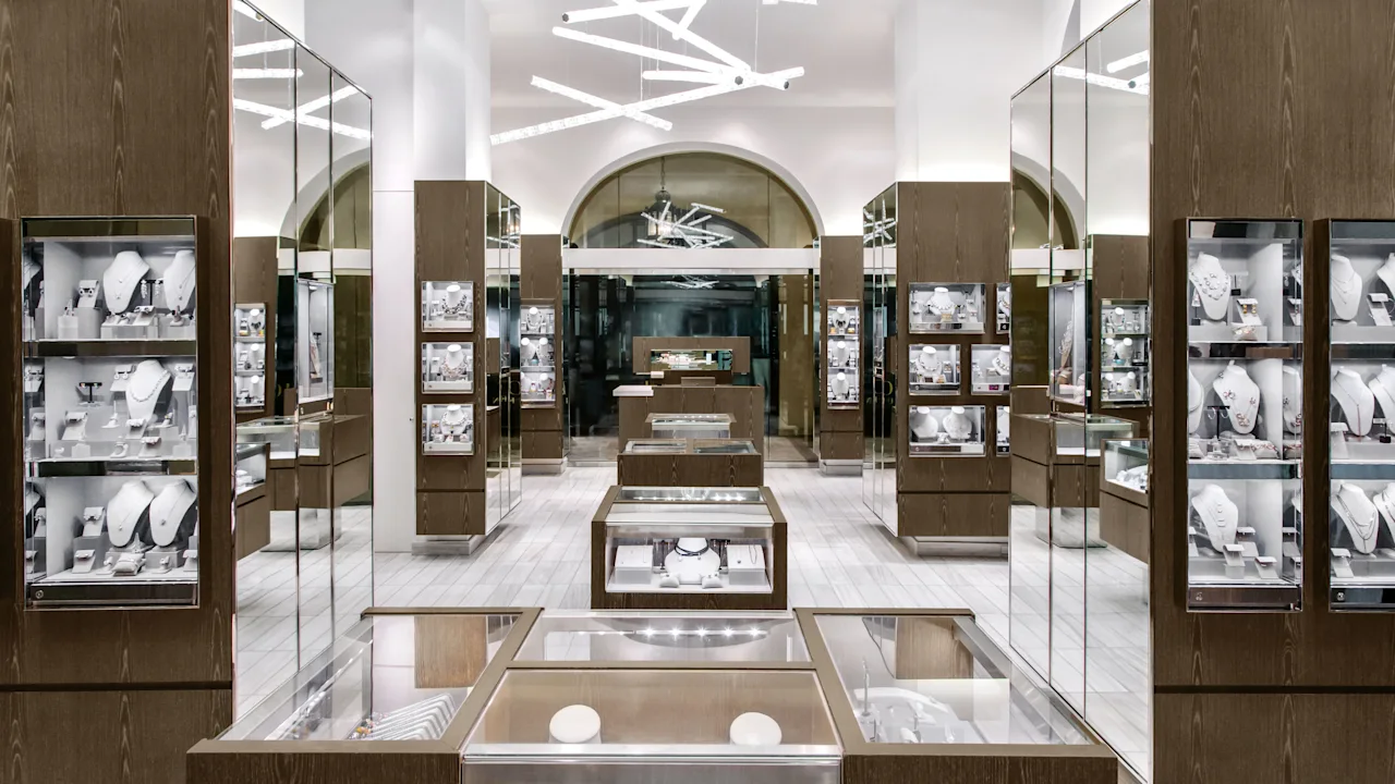 Modern jewelry store interior with wood and glass display cases, white walls, and geometric lighting.