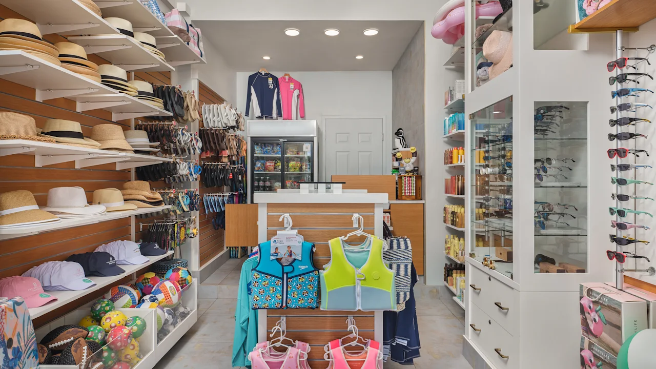 Bright retail store interior with hats, sunglasses, children's life vests, and beach accessories.