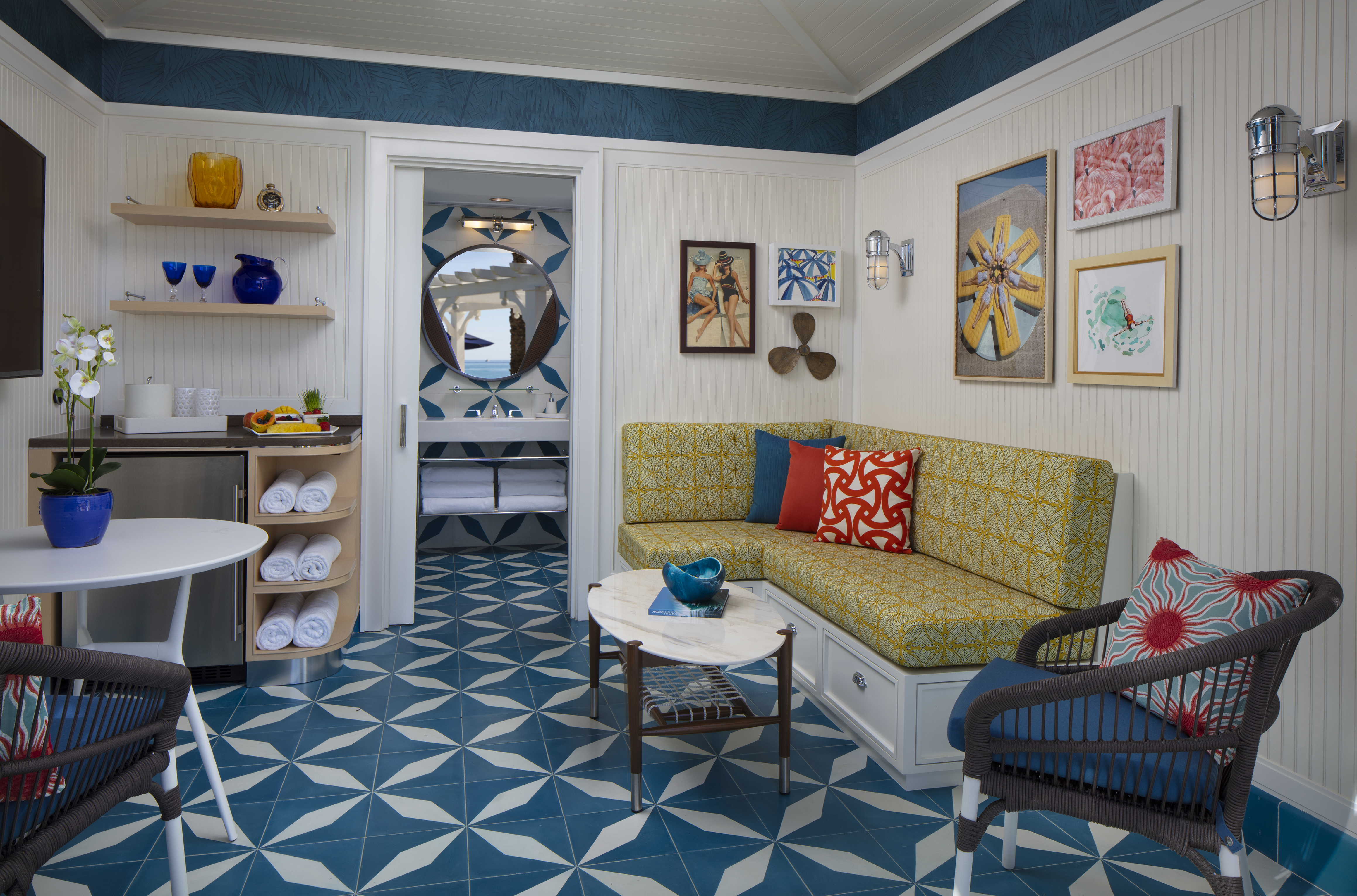 Colorful beach cottage interior with yellow sofa, teal geometric floor tiles, and nautical decor.