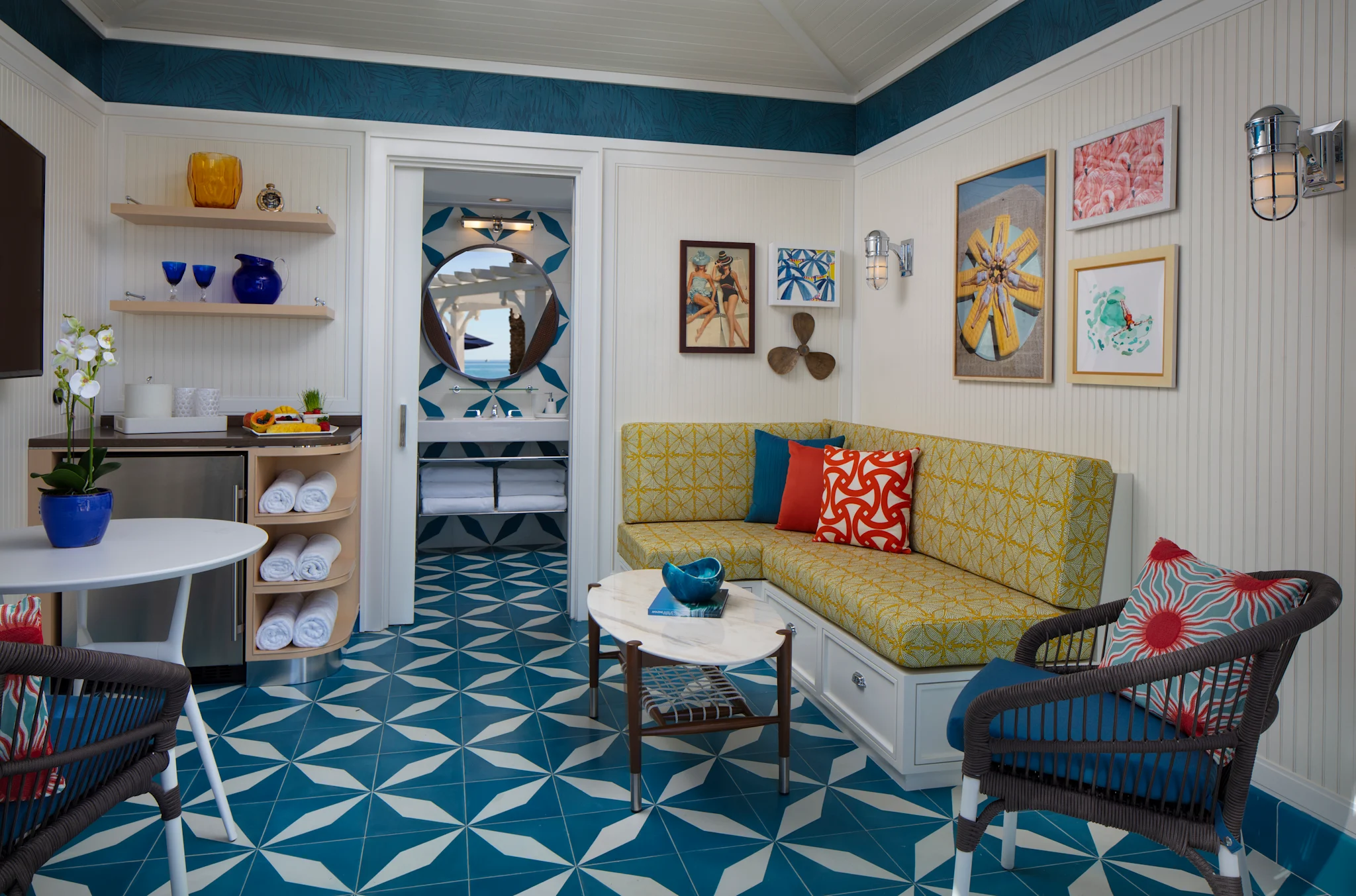 Colorful beach cottage interior with yellow sofa, teal geometric floor tiles, and nautical decor.