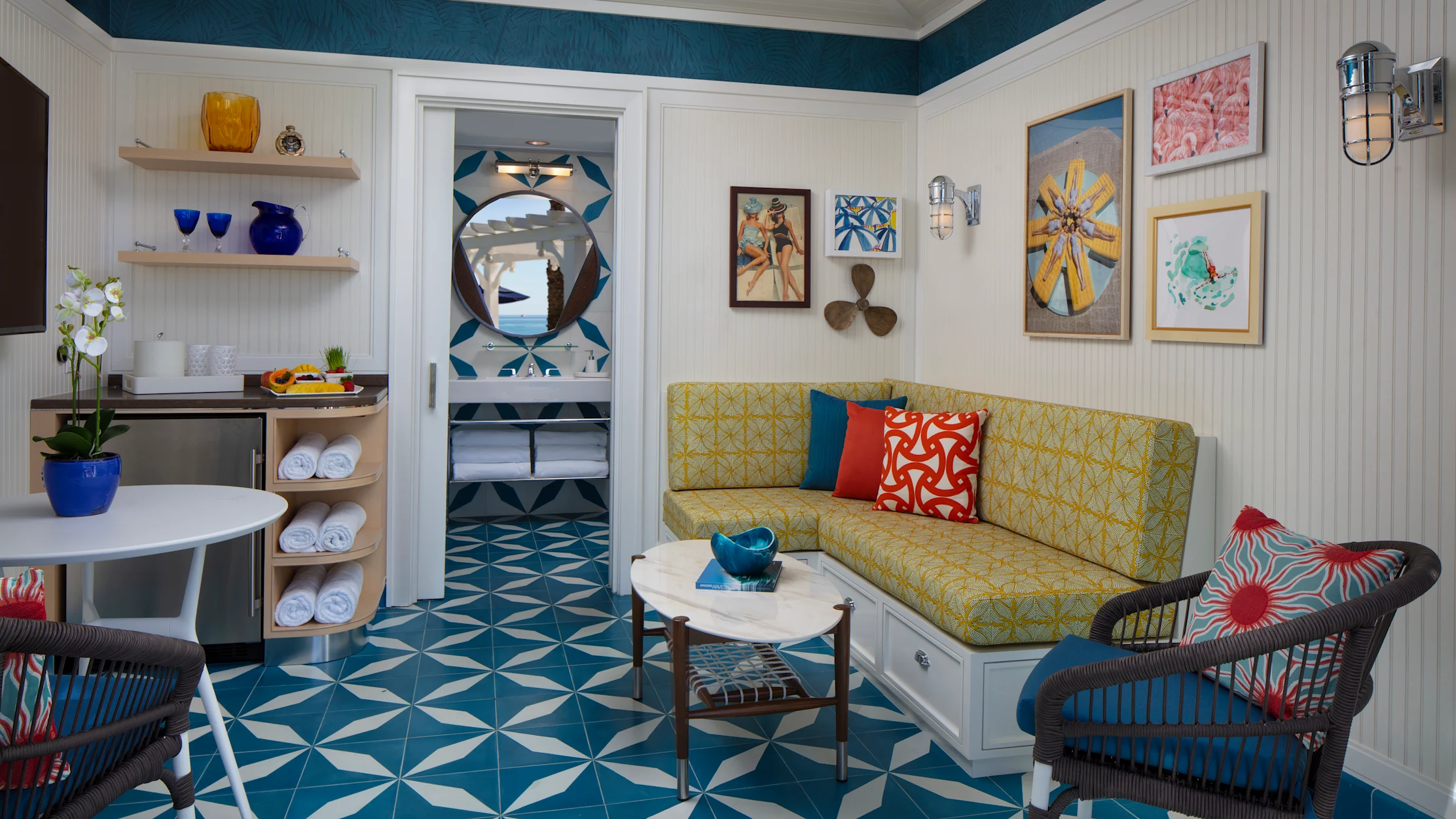 Colorful beach cottage interior with yellow sofa, teal geometric floor tiles, and nautical decor.