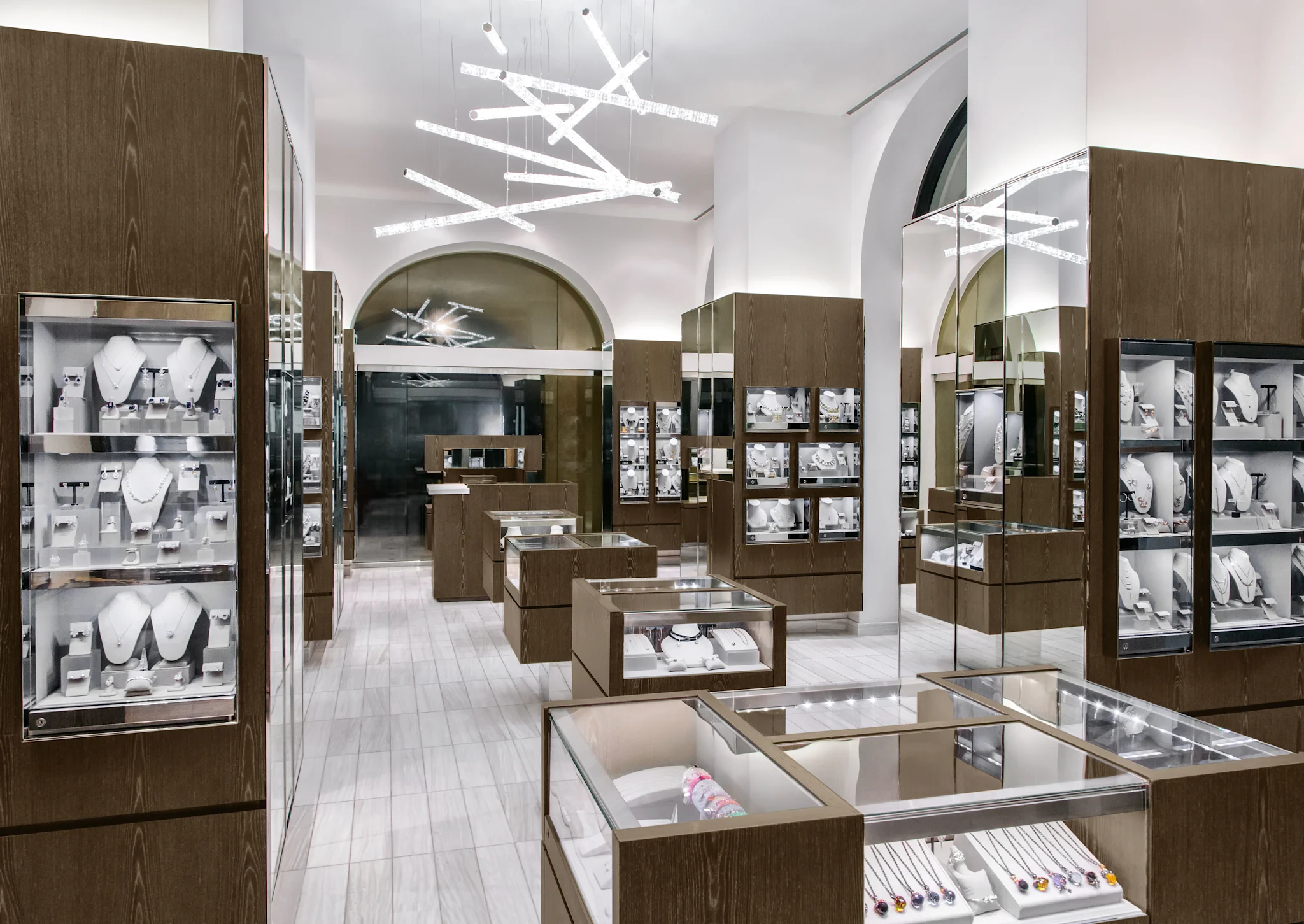 Modern jewelry store interior with wood display cases, white walls, and contemporary lighting fixture.