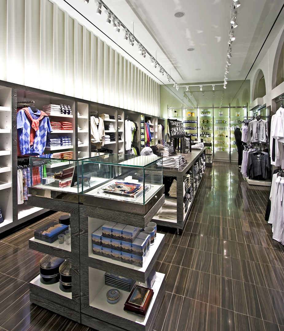 Modern retail clothing store interior with track lighting, wood floors, and organized displays.