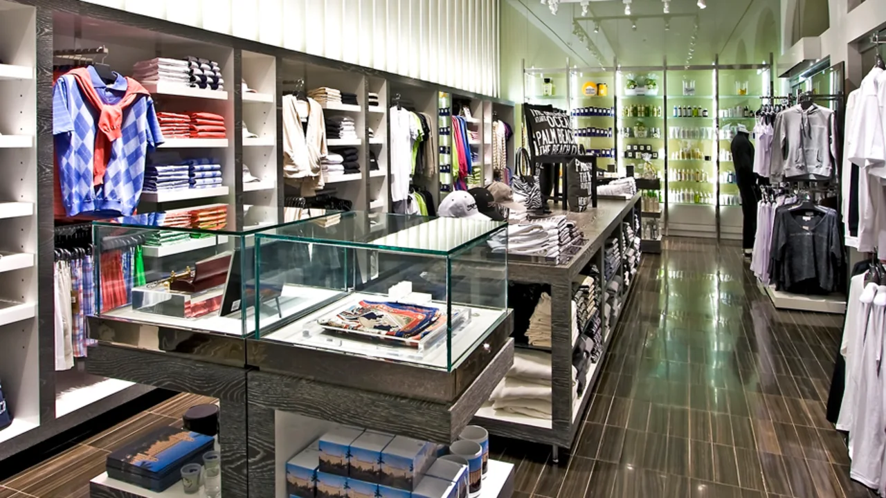 Modern retail clothing store interior with track lighting, wood floors, and organized displays.