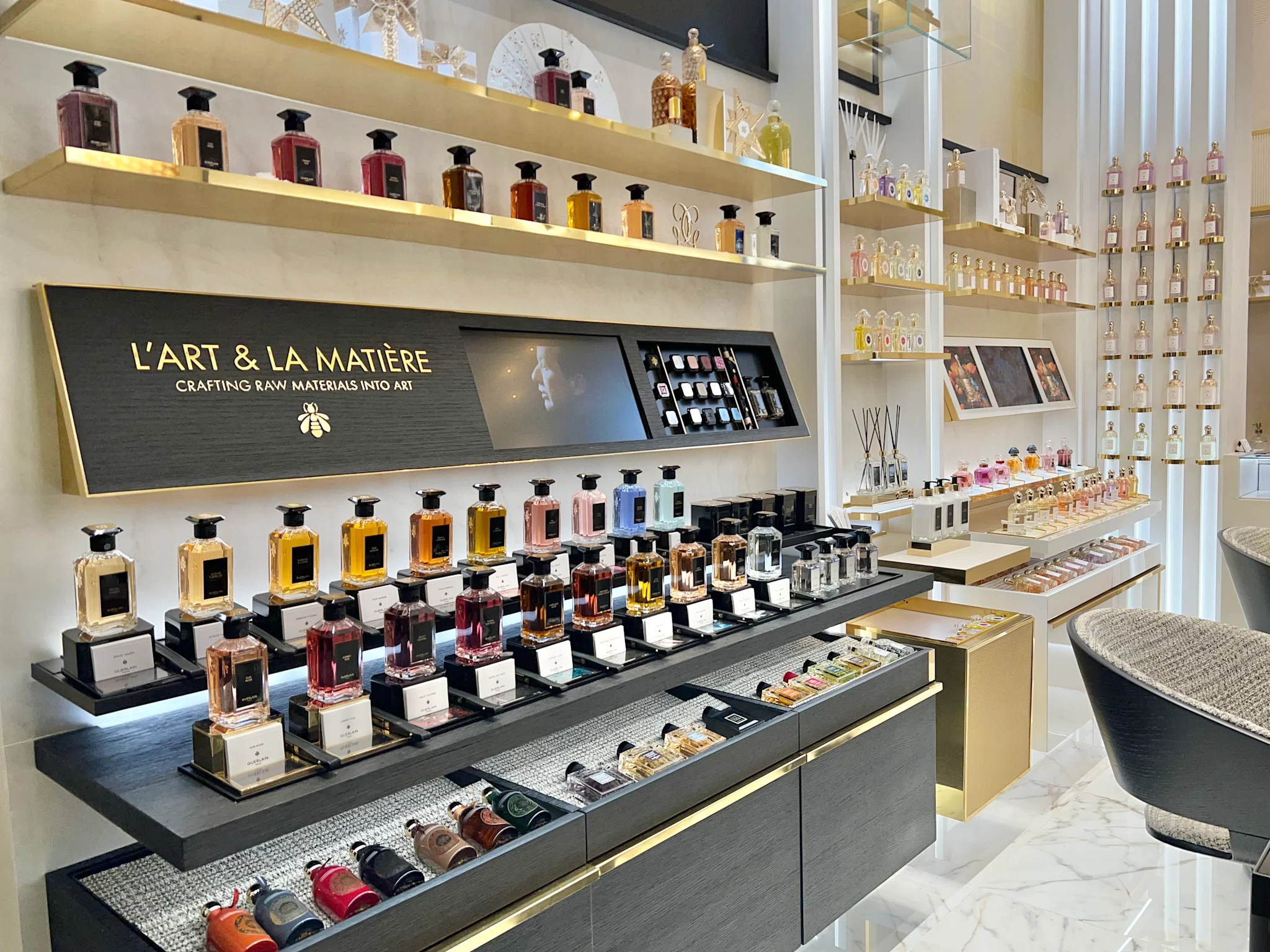 Luxury perfume store interior with L'ART & LA MATIÈRE display featuring colorful fragrance bottles on shelves.