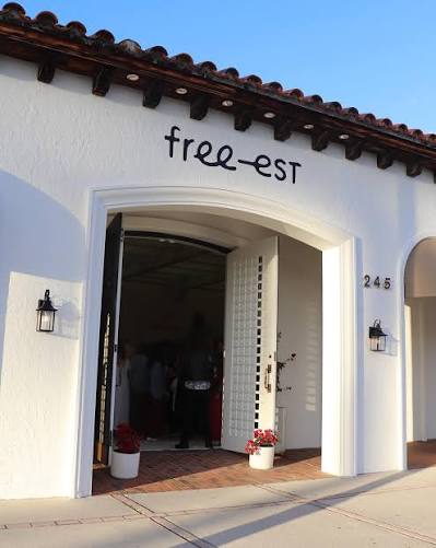White stucco storefront with red tile roof, open arched doorway, and free-est sign above entrance.